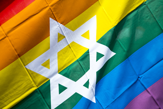 Photo of a LGBTQ+ flag with a white star of david on it