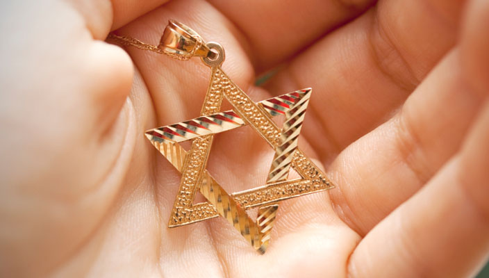A hand holding a Jewish star (Magen David) necklace