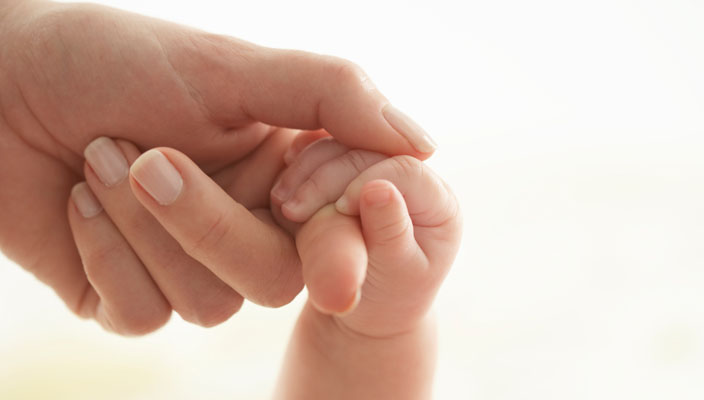 Parent holding the hand of an infant