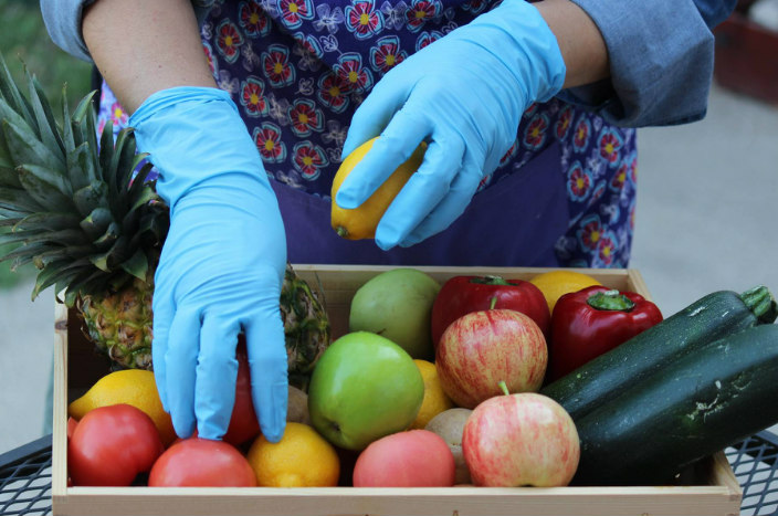 Gloved hands selecting vegetables