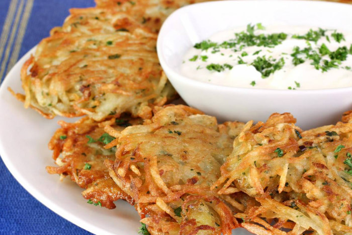 Fried potato pancakes in a circle around a small bowl of sour cream