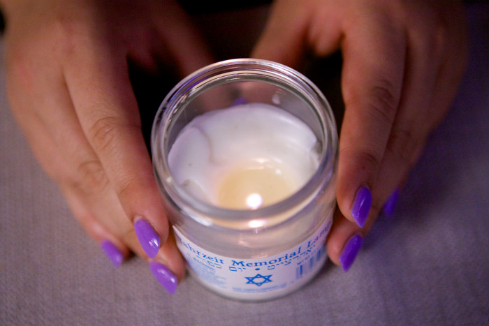 Aerial view of hands holding a Yahrzeit memorial candle 