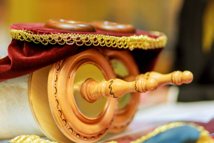 Torah scrolls with decorative mantel laying atop them