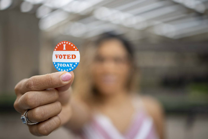 Blurred woman in the background holding to the foreground an I VOTED TODAY sticker