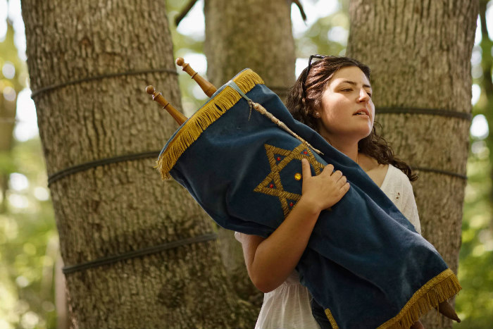 Young woman holding a Torah against trees