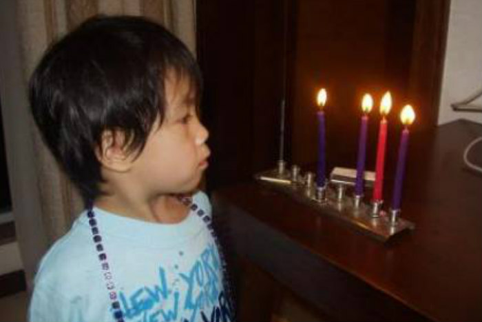 Young Asian child staring at a Hanukkah menorah