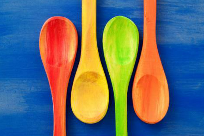 Four colorful wooden spoons against a blue background