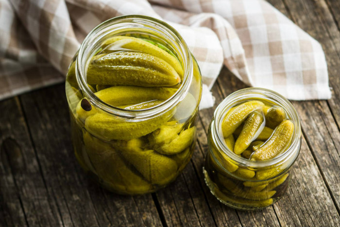 Two jars of pickles on a wooden surface