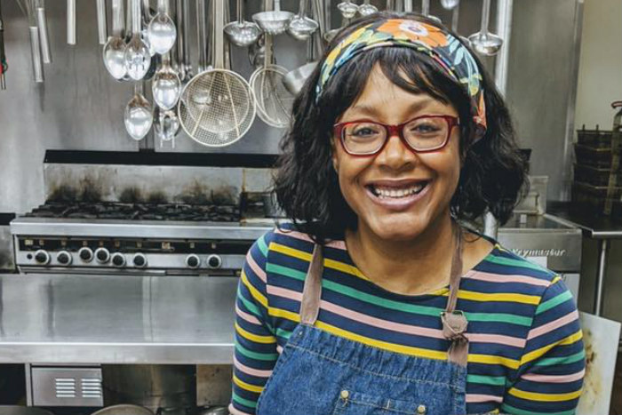 Chef Marisa Baggett smiles in front of a kitchen setting