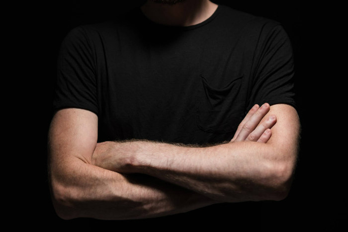 man with arms crossed in a black tshirt