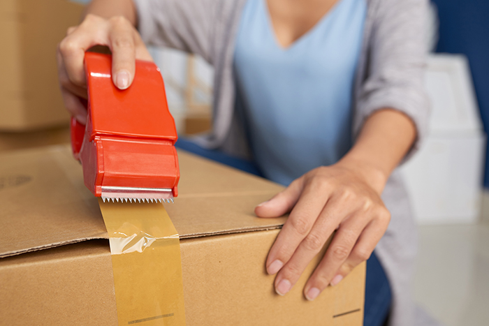 woman packing a box with tape