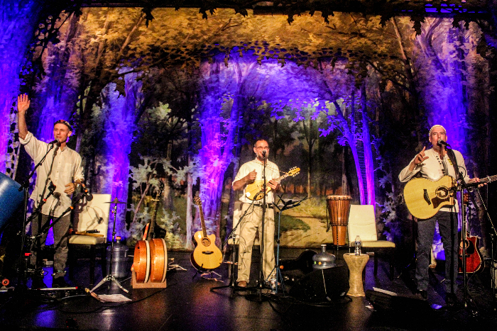 The three members of Abraham Jam performing on stage together with purple lighting behind them