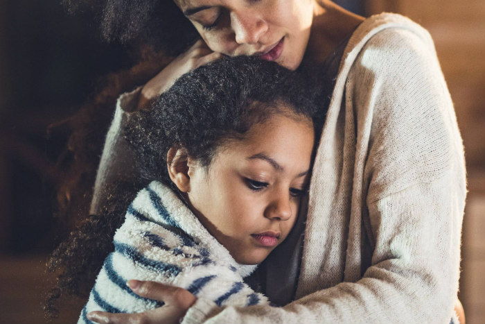 Young girl looking sad and hugging her mother 