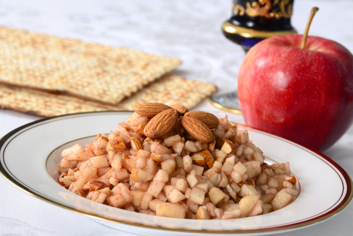 Bowl of charoset with almonds on top and a whole apple in the background 