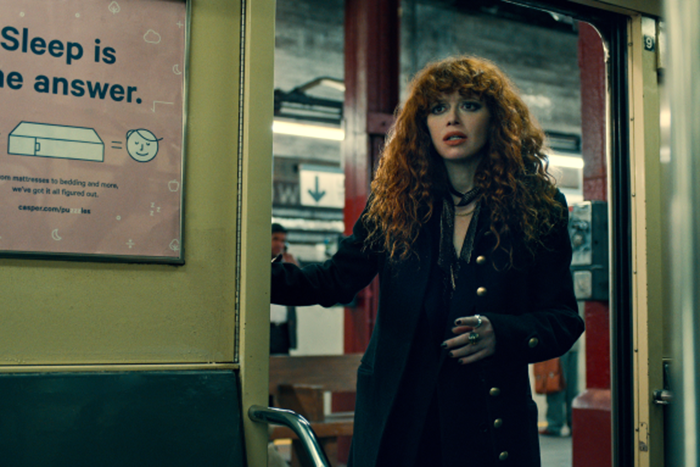 Natasha Lyon as Natasha Vulvokov entering a train