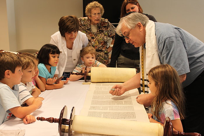 an image of a Rabbi reading from the Torah to a group of kids