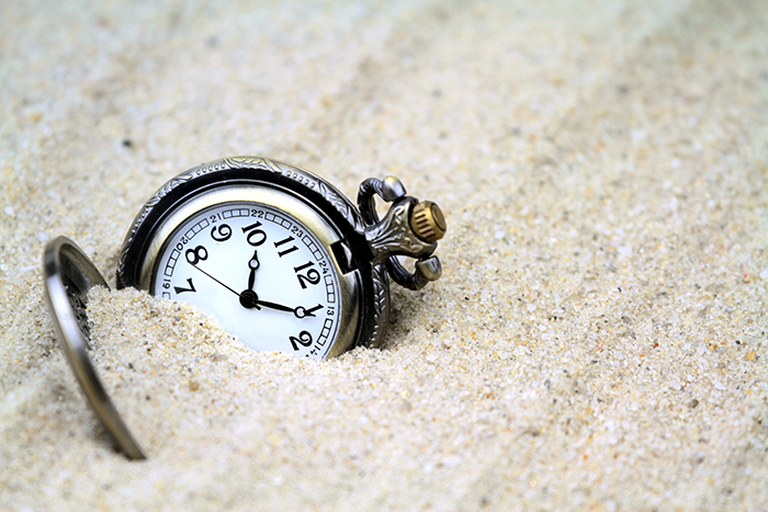 an image of a watch half burried in sand