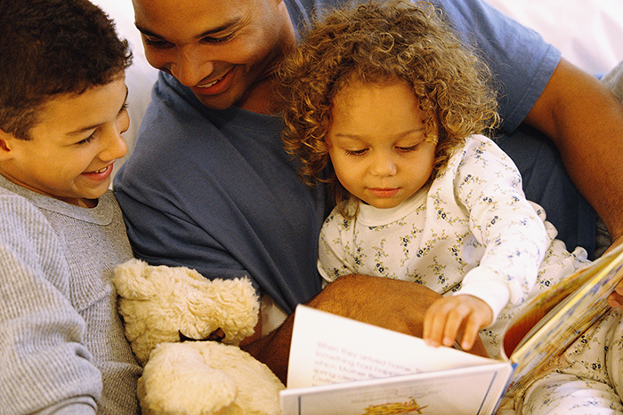 an image of a father and two kids reading a book