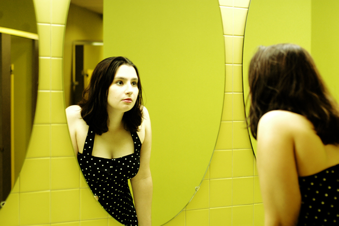an image of a young woman looking at her reflection in a mirror