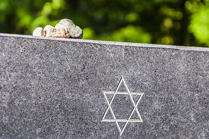 an image of a cement tombstone, with a star of david carved in and some rocks siting on top of the tombstone
