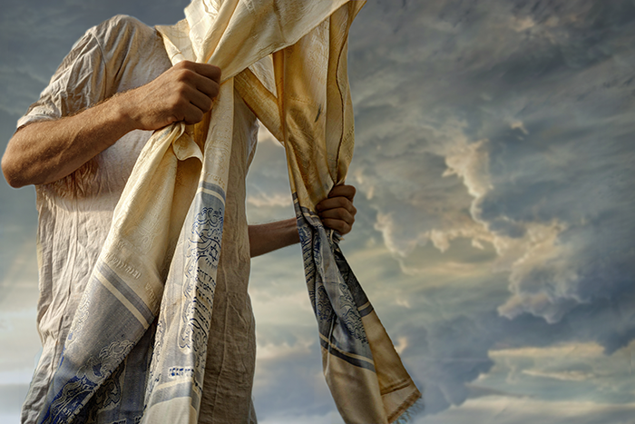 an image of a man holding a tallit over his head while praying