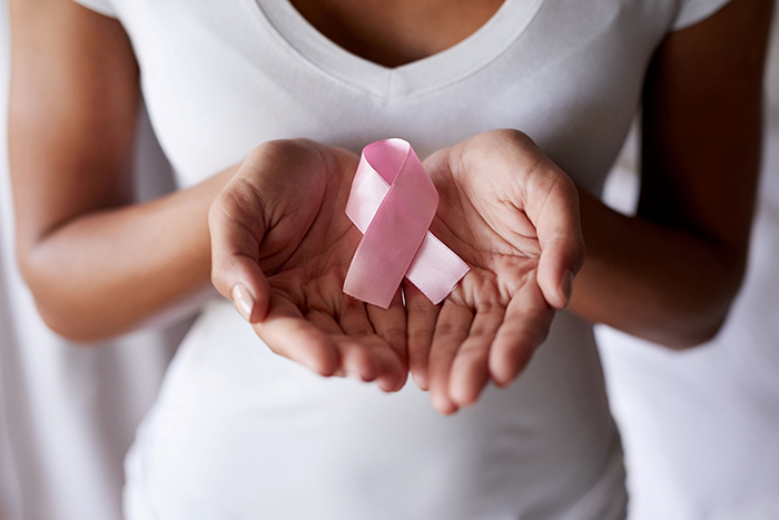 an image of a woman with a white shirt on holding a pink ribbon in her hands