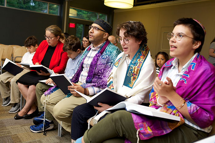 an image of a row of 6 people sitting in chairs praying