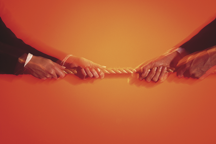 an image of two sets of hands tugging at the same rope