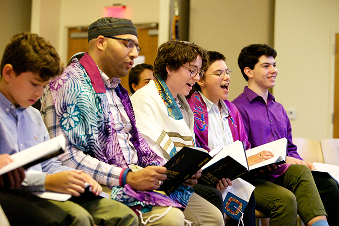 Photo of 5 people sitting in a sanctuary holding prayer books and praying