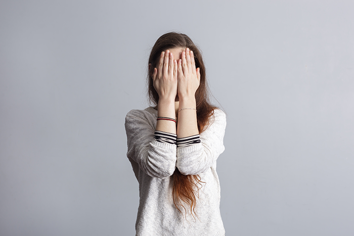 Photo of a girl covering her face with her hands