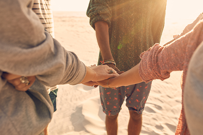 Photo of three people holding right hands in a circle