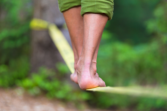 Photo of two feet walking on a tightrope