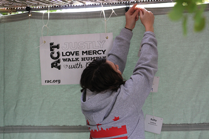 Photo of a woman hanging up the side of a sukkah
