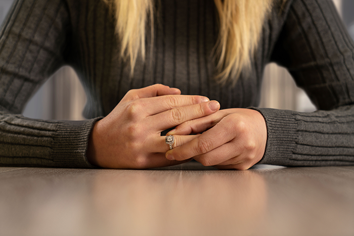 Photo of a woman's hands, sliding off her wedding ring