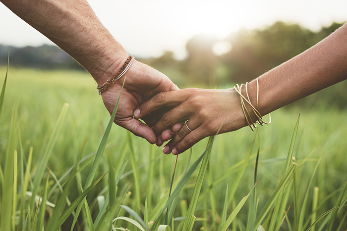 Photo of two people holding hands in a field