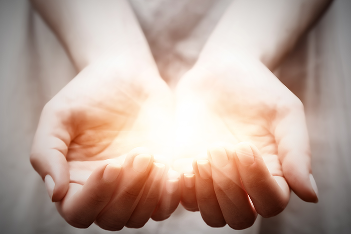 Photo of a light glowing in the palms of someone's hands