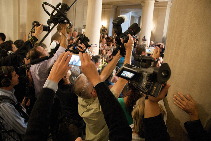Photo of a lot of photographers taking pictures in a room