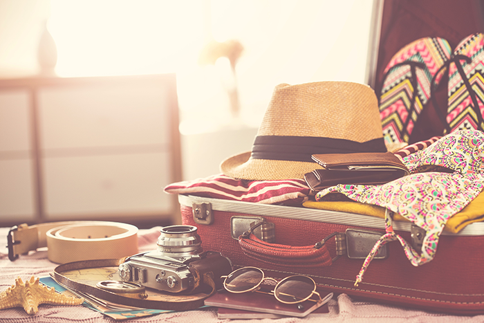 Photo of a suitcase full of typical travel stuff, like a camera, glasses and clothes