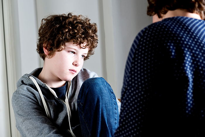 Photo of a parent talking to a young boy; boy looks sad