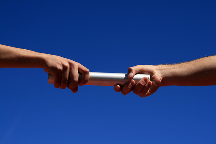 Photo of two hands passing a baton
