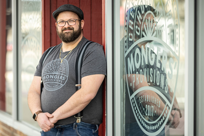 Photo of cheesemonger Zach Berg standing in front of his cheese store in Detroit