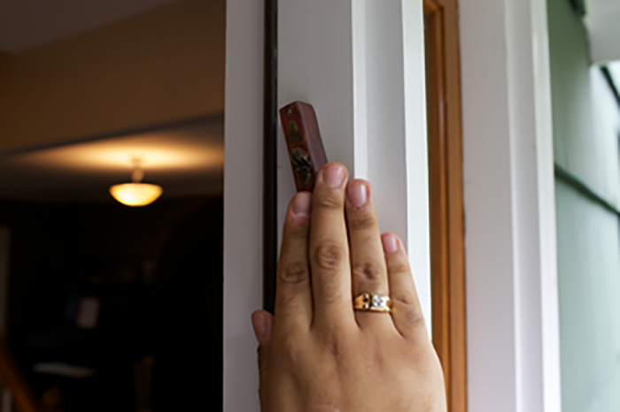 Photo of someone touching a mezuzah that is hanging in their front doorway