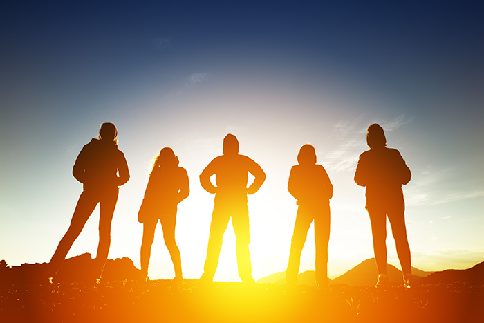 Photo of 5 human silhouette standing atop of moutain with the bright sun behind them