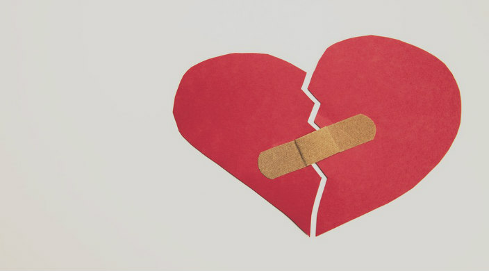 Construction paper rendering of a broken heart held together with a bandage 
