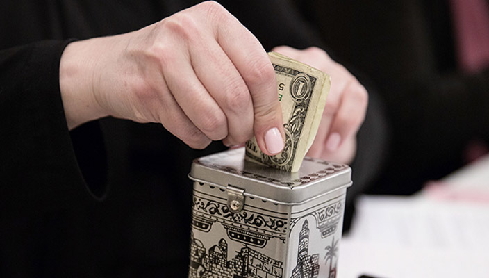 Putting money in a pushka, or charity donation box