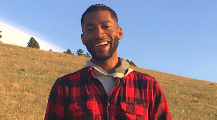 Smiling young man outdoors wearing a kippah and a plaid shirt