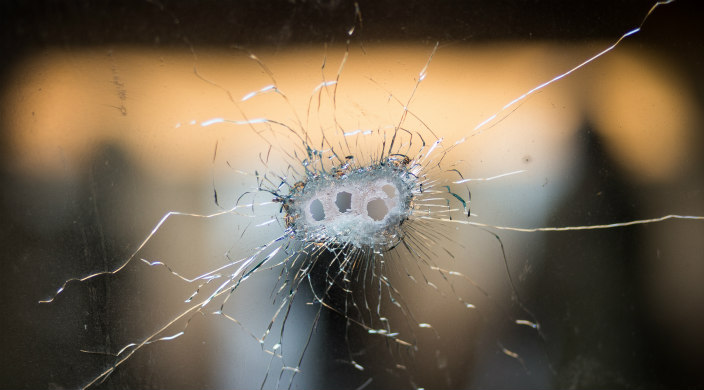 Four bullet holes close together in a pane of glass 