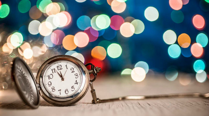 Open pocketwatch with clock face visible in front of blurred and colorful confetti