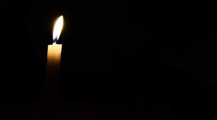 Lighted candle flickering in total darkness