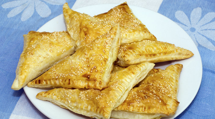 Cheese burekas on a white plate with a blue tablecloth underneath